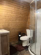 Full bath featuring a stall shower, lofted ceiling, and stone tile floors