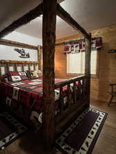 Bedroom featuring a textured ceiling, wooden walls, and wood finished floors