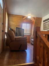 Living area with wooden walls, wood finished floors, and a textured ceiling