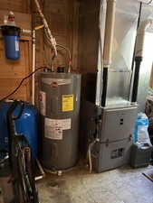 Utility room featuring electric water heater and heating unit