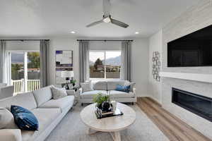 Living area with wood finished floors, a textured ceiling, a fireplace, a ceiling fan, and recessed lighting