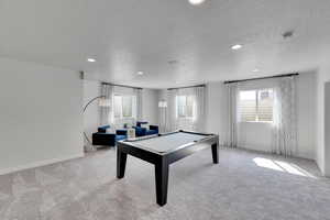 Recreation room with light colored carpet, plenty of natural light, a textured ceiling, recessed lighting, and billiards
