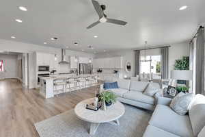 Living room with a ceiling fan, recessed lighting, light wood finished floors, and a chandelier