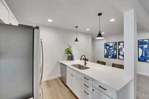 Kitchen featuring white cabinets, stainless steel appliances, a peninsula, pendant lighting, and recessed lighting