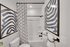 Full bathroom featuring shower / bathtub combination with curtain and toilet