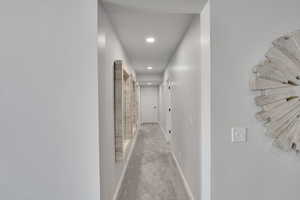 Hallway featuring light colored carpet and recessed lighting