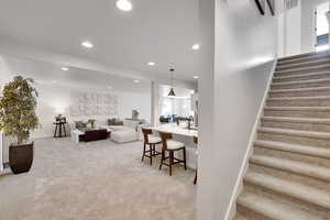 Living room featuring stairway, light carpet, recessed lighting, and a textured ceiling