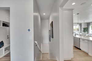 Hall with light wood finished floors, a textured ceiling, an upstairs landing, and recessed lighting