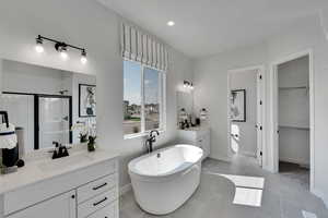 Bathroom with a shower stall, two vanities, a freestanding bath, light tile patterned floors, and recessed lighting