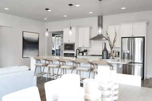 Kitchen with a breakfast bar area, an island with sink, stainless steel appliances, light stone counters, and recessed lighting