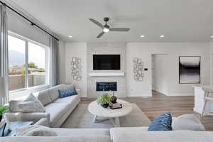 Living room with a ceiling fan, light wood finished floors, a fireplace, recessed lighting, and a mountain view
