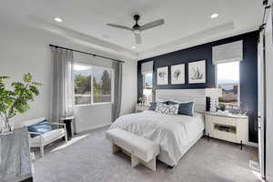 Carpeted bedroom with a tray ceiling, a barn door, a ceiling fan, and recessed lighting