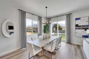 Dining area with light wood finished floors, a chandelier, plenty of natural light, and a textured ceiling