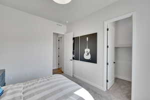 Bedroom featuring light colored carpet and a walk in closet