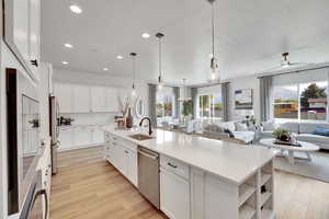 Kitchen featuring open shelves, white cabinets, pendant lighting, stainless steel appliances, and light wood-style floors