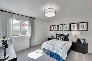 Bedroom featuring a textured ceiling and light colored carpet