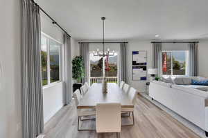 Dining room with light wood-style flooring, a chandelier, and a textured ceiling