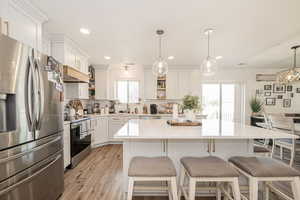 Kitchen with stainless steel appliances, open shelves, pendant lighting, backsplash, and white cabinets