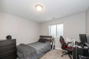Bedroom with light colored carpet and a desk