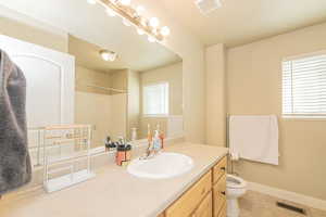 Full bath featuring vanity, light tile patterned flooring, healthy amount of natural light, and a shower
