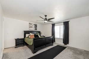 Bedroom with light colored carpet, a textured ceiling, and a ceiling fan