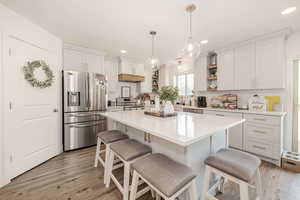 Kitchen with appliances with stainless steel finishes, a kitchen breakfast bar, a center island, light wood-style flooring, and recessed lighting