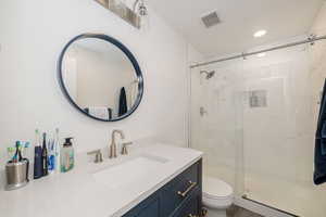 Bathroom with a stall shower, vanity, and recessed lighting