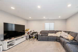 Living area with light carpet and recessed lighting