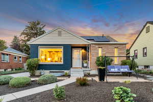 Bungalow featuring brick siding, roof mounted solar panels, a patio, and an outdoor living space
