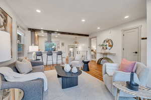 Living room with beam ceiling, recessed lighting, and wood finished floors