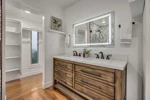 Full bath featuring double vanity, light wood-style flooring, and a shower