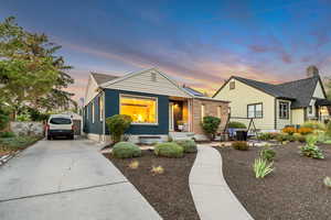 View of front of property featuring concrete driveway, brick siding, and a chimney