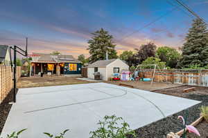 View of basketball court featuring a patio, a fenced backyard, a playground, and basketball court