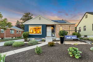 Bungalow-style home featuring brick siding, solar panels, and a patio