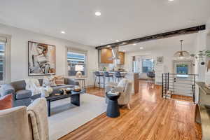 Living room with beam ceiling, light wood-style flooring, recessed lighting, and plenty of natural light
