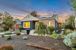 View of front of property with solar panels, a patio, brick siding, and a shingled roof