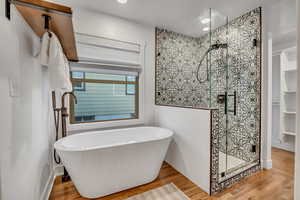Full bathroom with a shower stall, light wood-style floors, a freestanding bath, and recessed lighting