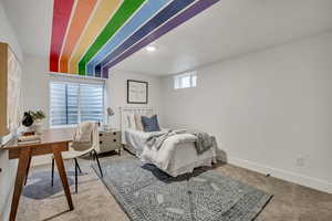 Carpeted bedroom featuring baseboards and a desk