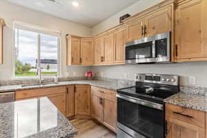 Kitchen featuring stainless steel appliances, light stone countertops, light brown cabinets, light wood-style floors, and recessed lighting