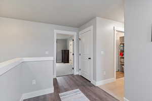 Corridor featuring an upstairs landing and dark wood finished floors