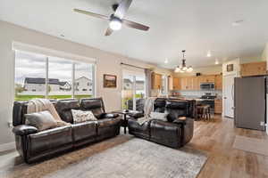 Living area featuring light wood finished floors, a chandelier, and ceiling fan