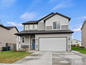 Traditional-style home featuring concrete driveway, a front lawn, a garage, and a porch