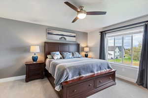 Bedroom with light colored carpet and a ceiling fan