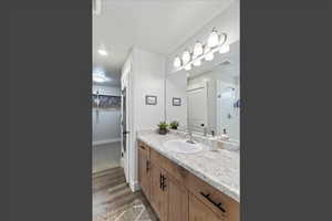 Full bathroom with vanity, a shower stall, a spacious closet, and light wood-type flooring