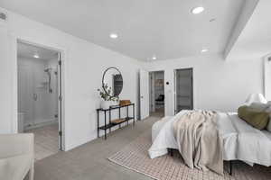 Primary Bedroom featuring a walk in closet, recessed lighting, light carpet, and ensuite bath