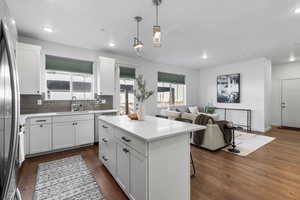 Kitchen featuring white cabinets, a center island, open floor plan, tile backsplash, and pendant lighting