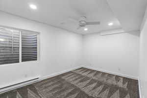 Downstairs bedroom featuring baseboard heating, dark colored carpet, recessed lighting, and a ceiling fan