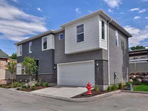 Contemporary house with stucco siding, brick siding, a garage, and concrete driveway