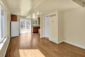 Kitchen featuring brown cabinets, freestanding refrigerator, a textured ceiling, and light wood-style flooring