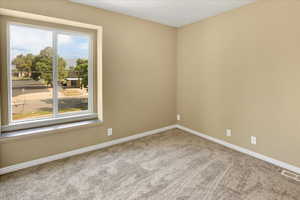 Empty room with baseboards and light colored carpet